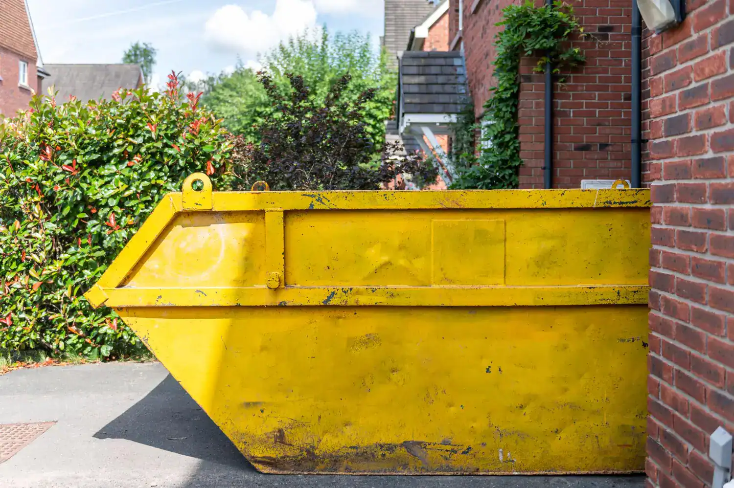 Yellow dumpster placed on driveway next to brick house in Illinois.