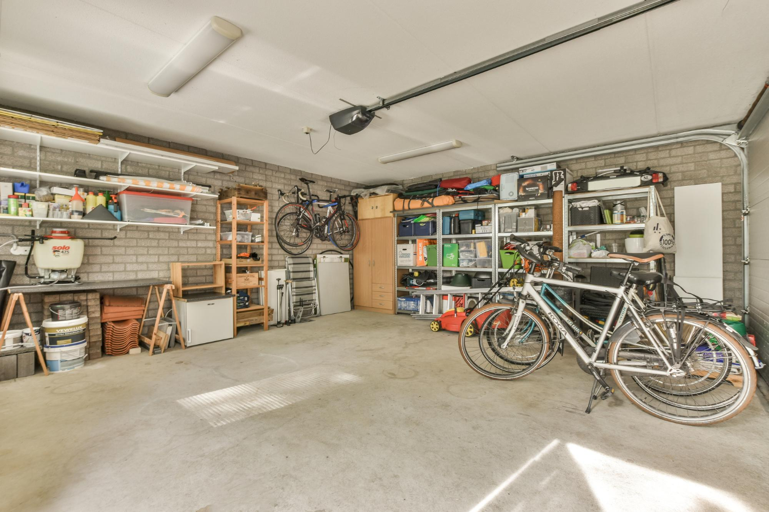 Garage interior with organized shelves, bicycles, and storage bins, illustrating a space ready for a spring cleanout with EcoBox Dumpsters.