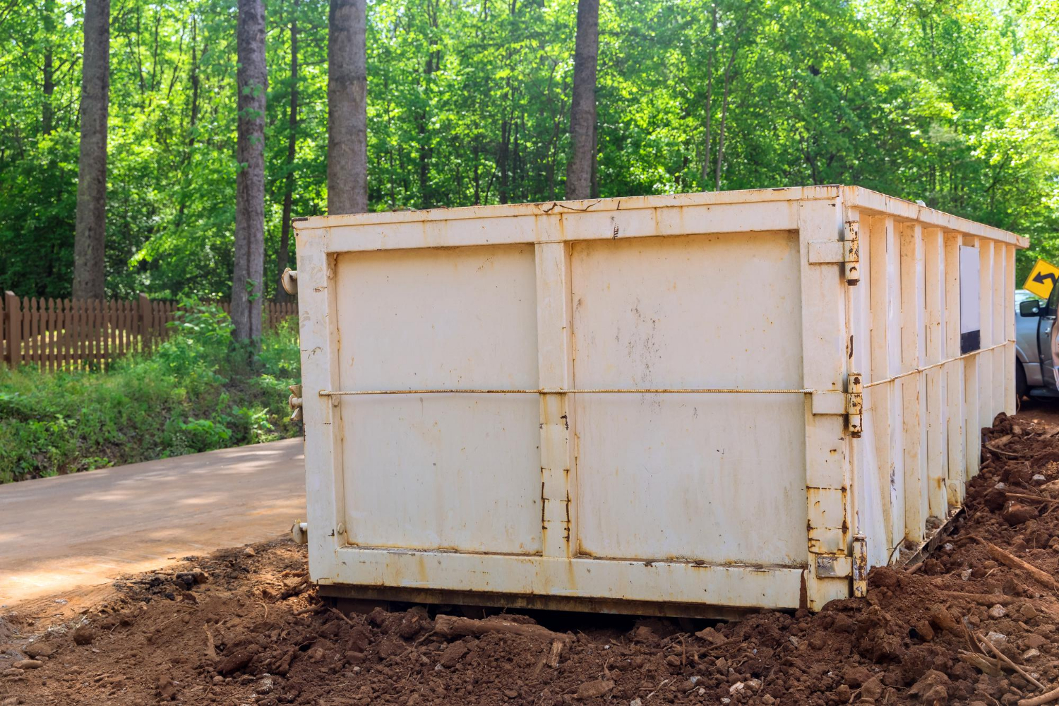 Construction dumpster on a job site surrounded by trees, illustrating waste management solutions for construction projects in Illinois.
