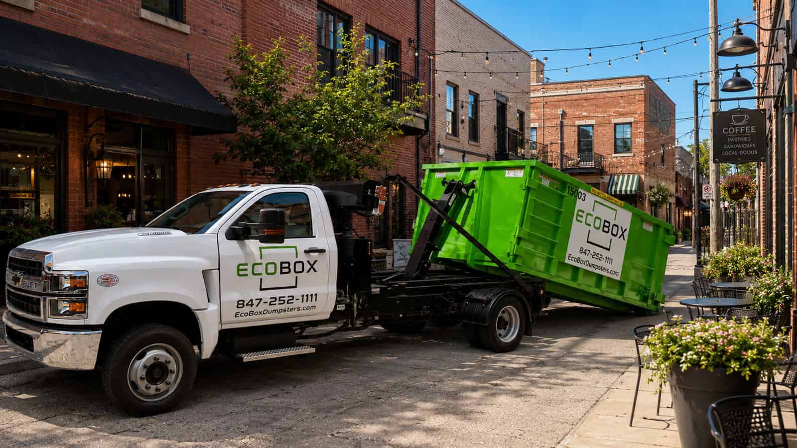 EcoBox truck placing a green dumpster in a service alley