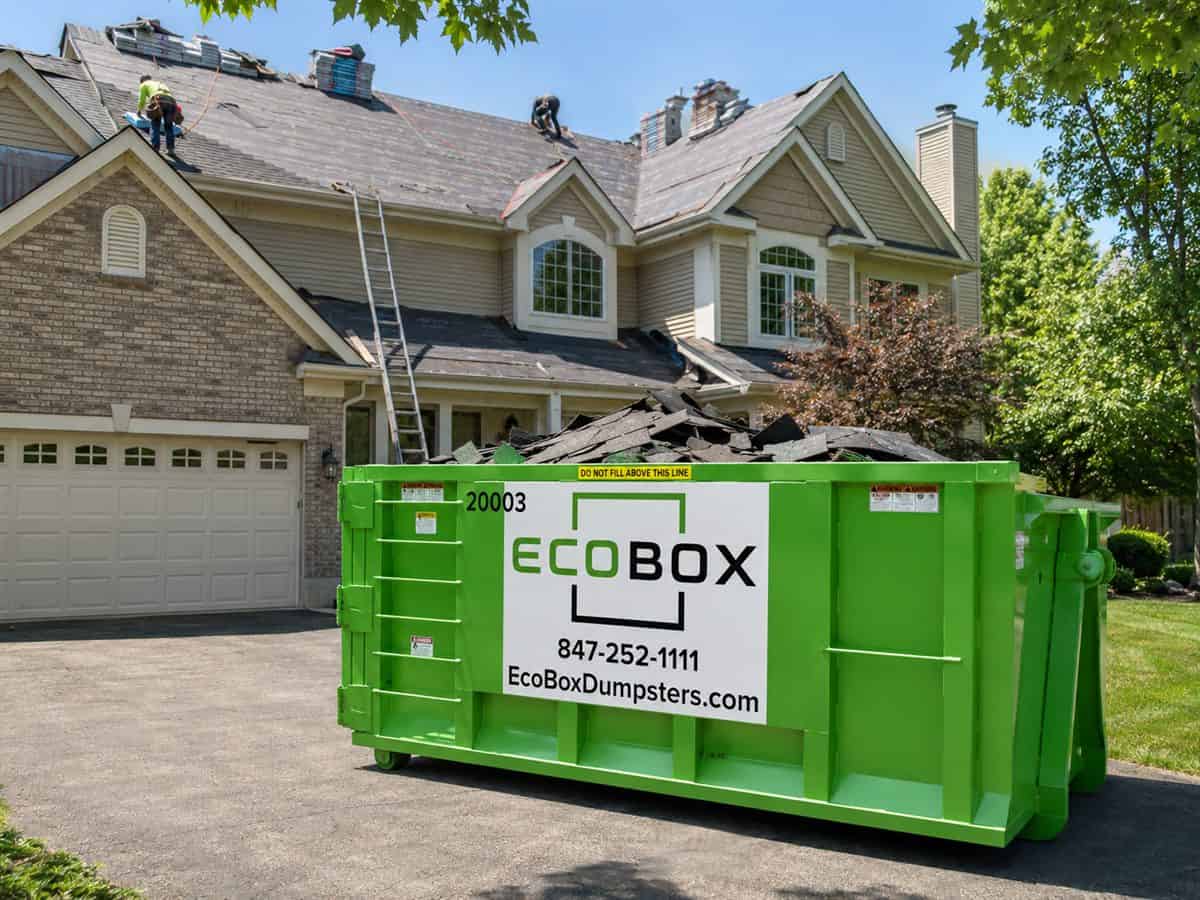 A roll-off dumpster on a residential driveway during a shingle tear-off