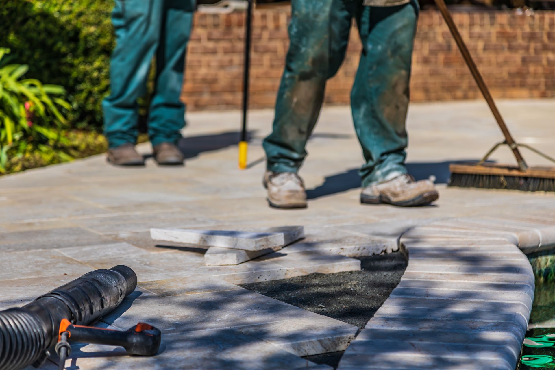 Workers cleaning hardscape debris and pavers for DIY project and dumpster rental