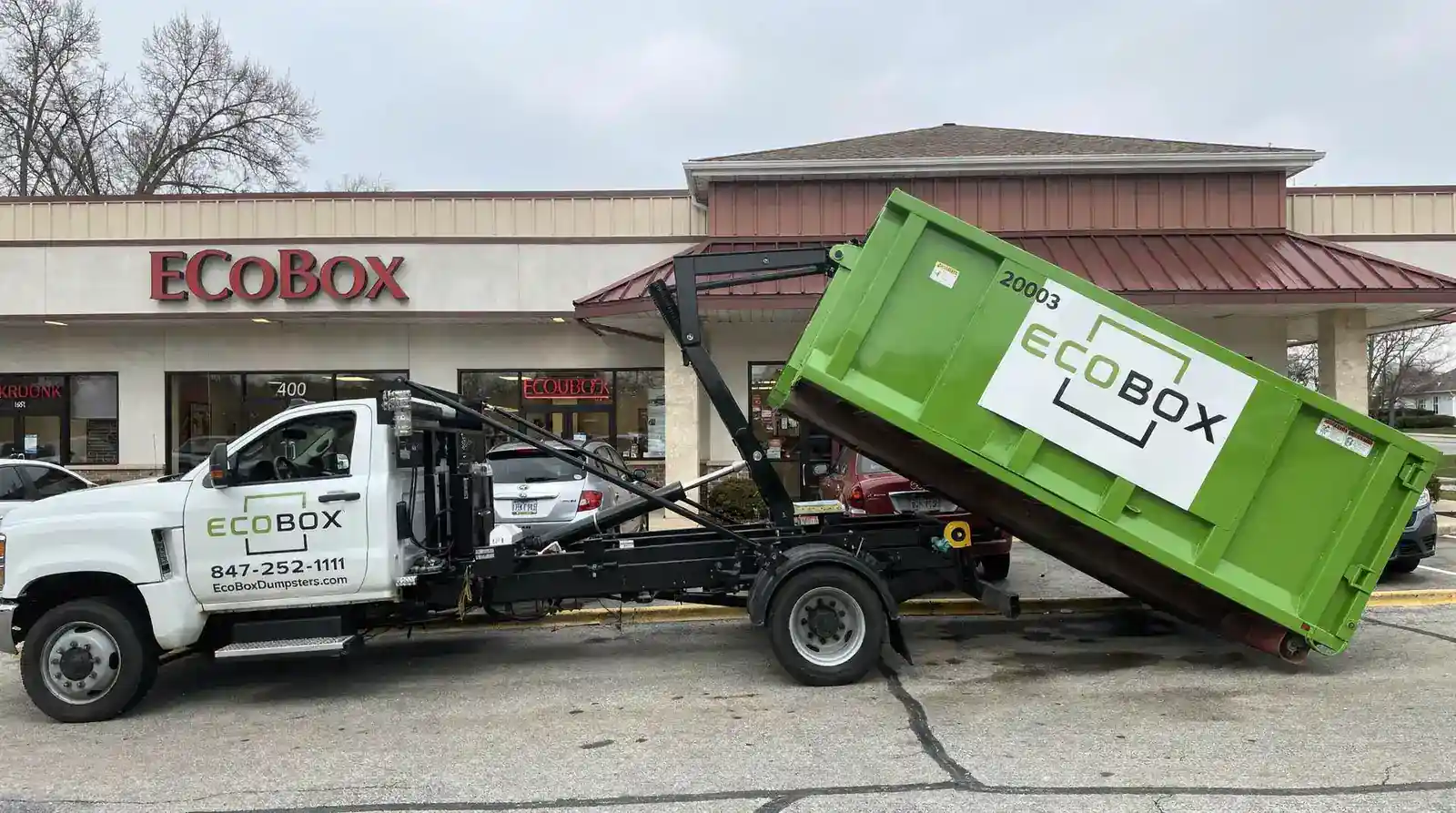EcoBox Dumpster service truck with green dumpster outside EcoBox store.